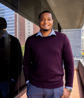 man standing next to the JFK school of Law building